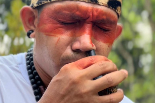 Indigenous man blowing Hapé through a kuripe – traditional Amazonian snuff ritual for healing and spiritual connection